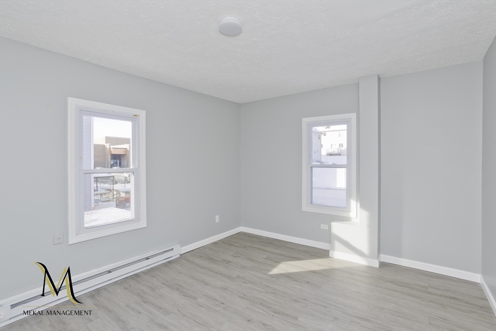 131 Center Street, Unit 131 Holyoke, MA 01040 - Photo 3 of 12 a view of an empty room with wooden floor and a window