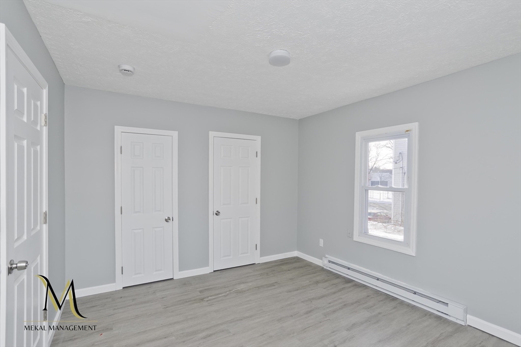 131 Center Street, Unit 131 Holyoke, MA 01040 - Photo 4 of 12 a view of an empty room with window and wooden floor