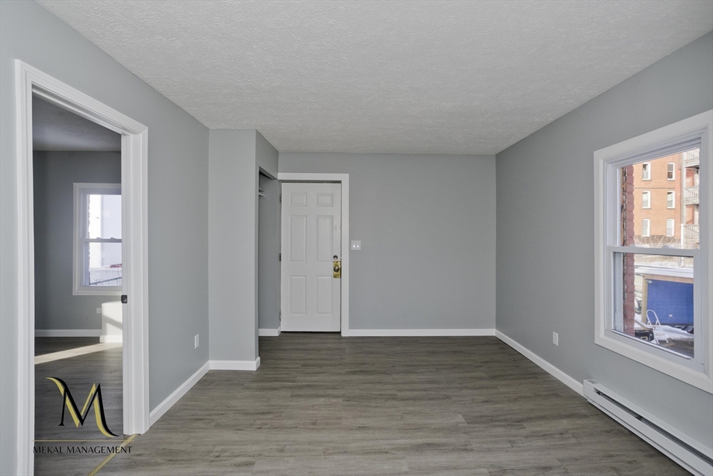 131 Center Street, Unit 131 Holyoke, MA 01040 - Photo 5 of 12 a view of an empty room with wooden floor and a window