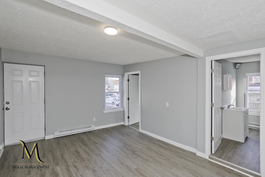 131 Center Street, Unit 131 Holyoke, MA 01040 - Photo 6 of 12 an empty room with wooden floor and windows