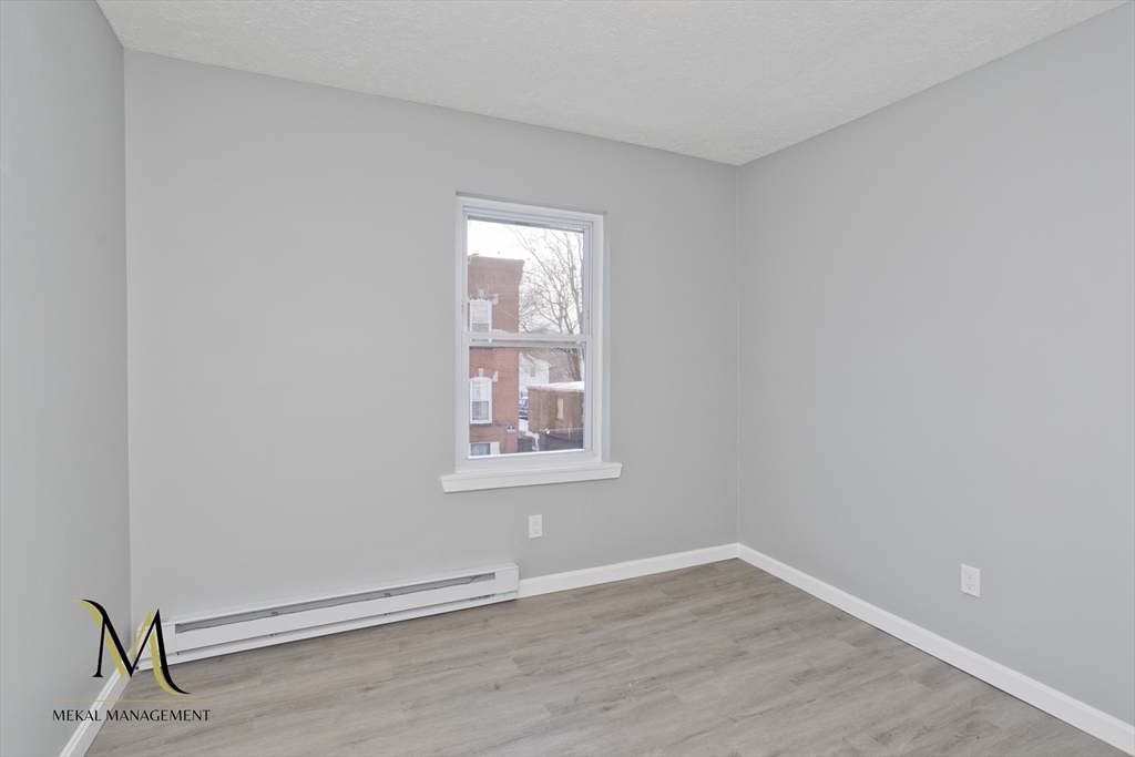 131 Center Street, Unit 131 Holyoke, MA 01040 - Photo 10 of 12 an empty room with wooden floor and windows