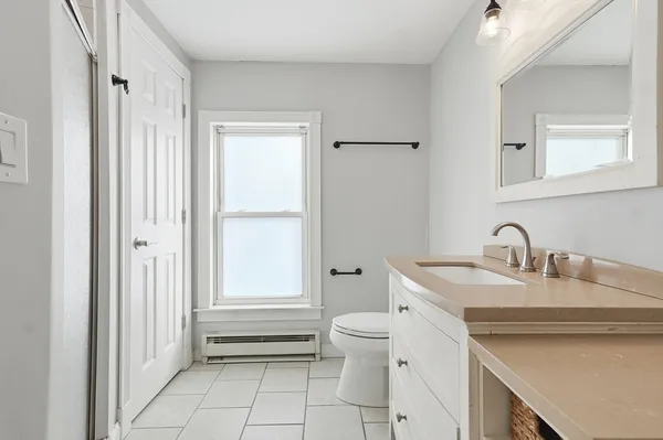 a bathroom with a granite countertop sink a toilet and a shower