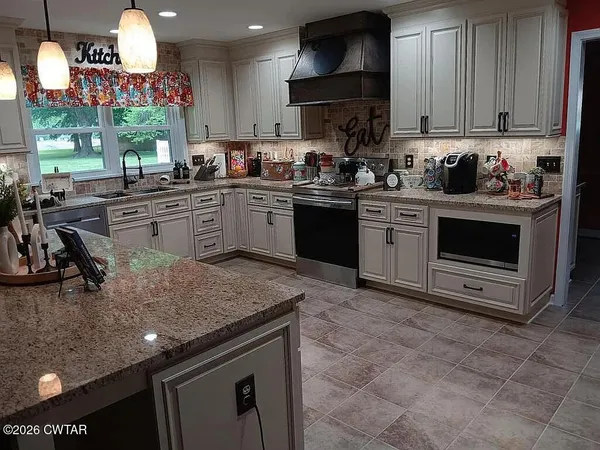 a kitchen with stainless steel appliances granite countertop a sink a stove and a microwave