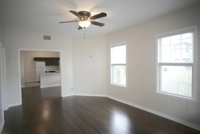 a view of an empty room with wooden floor and a window