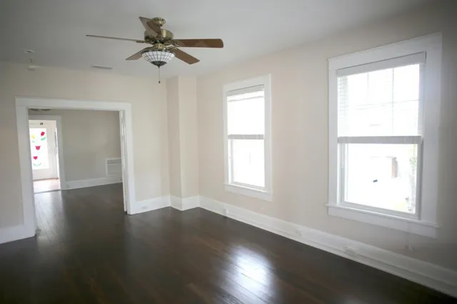 an empty room with wooden floor and windows