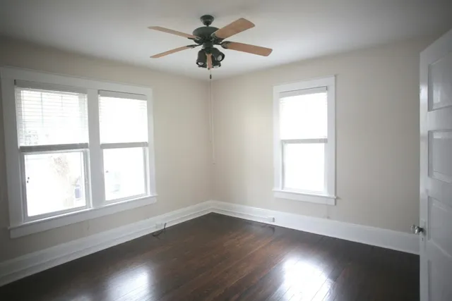 a view of an empty room with a window and wooden floor