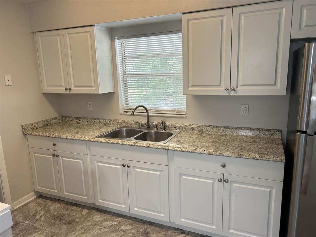 1241 Pilgrim Road Spring Hill, FL 34606 - Photo 10 of 28 a kitchen with granite countertop white cabinets and sink