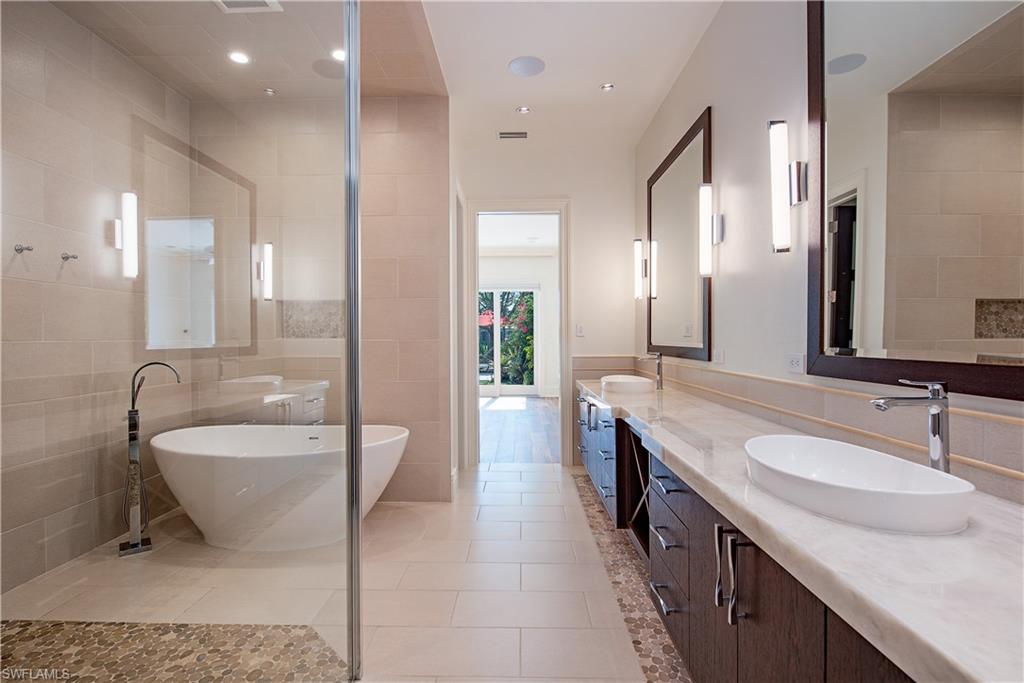 7100 Verde Way Naples, FL 34108 - Photo 11 of 18 a bathroom with a double vanity sink a mirror and a bathtub