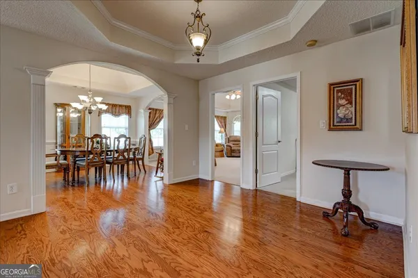 a view of a hallway with wooden floor and chandelier