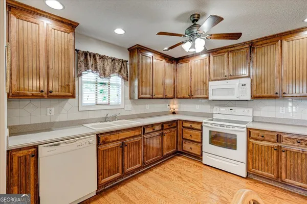 a large white kitchen with stainless steel appliances granite countertop a stove and a wooden floors