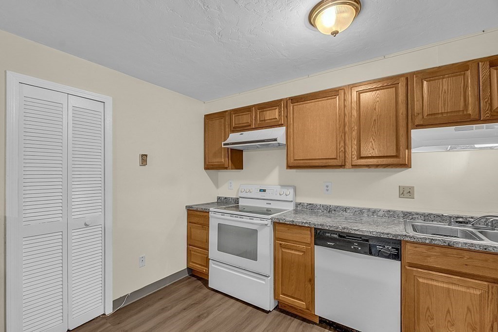 11 Gibbs Street, Unit A6 Worcester, MA 01607 - Photo 9 of 26 a kitchen with stainless steel appliances granite countertop a sink and cabinets with wooden floor
