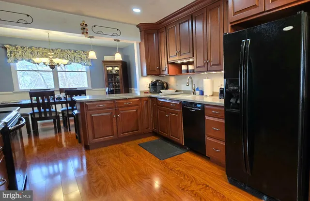 a kitchen with stainless steel appliances granite countertop a sink wooden cabinets dining table and chairs