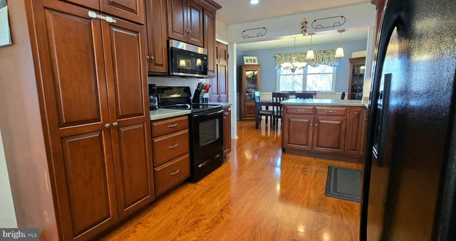 a kitchen with stainless steel appliances granite countertop a refrigerator and a wooden floor