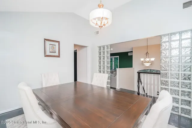 a kitchen with stainless steel appliances kitchen island granite countertop a dining table chairs and a refrigerator