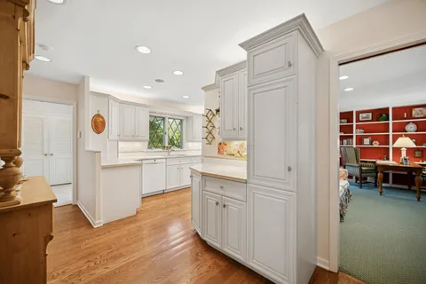 a kitchen with white cabinets and wooden floor