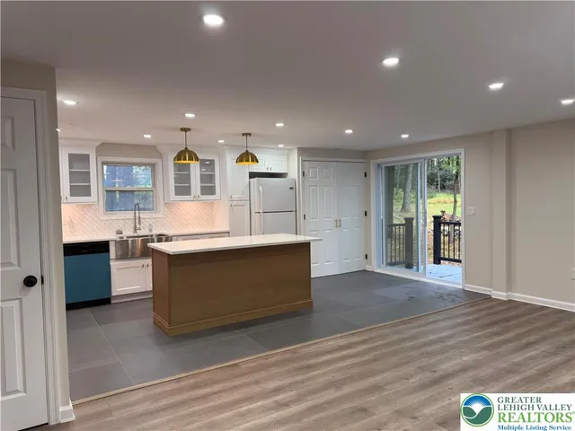 a large room with kitchen island wooden floors and stainless steel appliances
