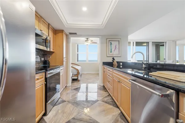 a large white kitchen with stainless steel appliances granite countertop a stove a sink and a microwave