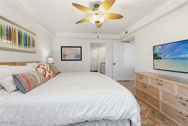 a bedroom with a bed a flat screen tv and a book shelf