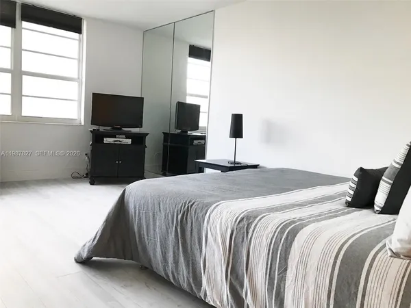 a bedroom with a bed and a flat tv screen on a dresser
