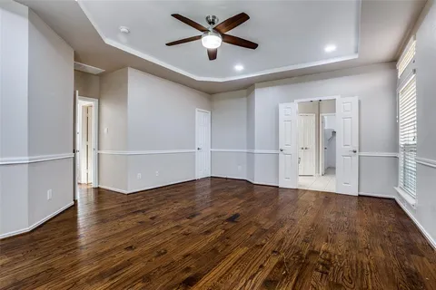 an empty room with wooden floor and a ceiling fan