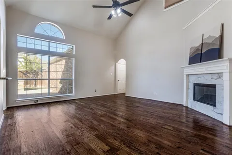 an empty room with wooden floor fireplace and windows