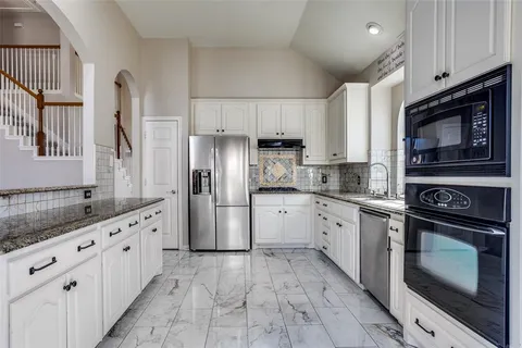 a kitchen with granite countertop a refrigerator stove and sink