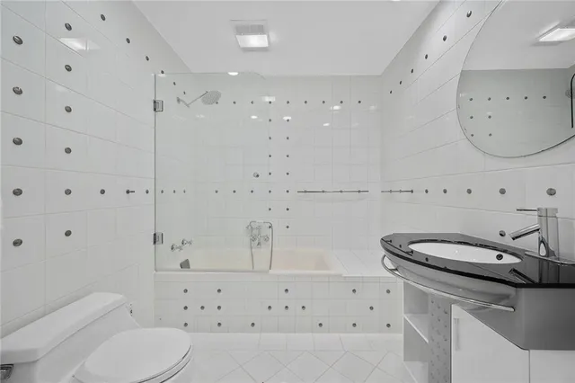 a large bathroom with a double vanity sink a toilet a mirror and shower