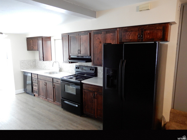 490 Averett Avenue Springville, UT 84663 - Photo 4 of 14 Kitchen featuring dark wood cabinetry, light countertops, a mosaic tile backsplash, and wood-finish flooring