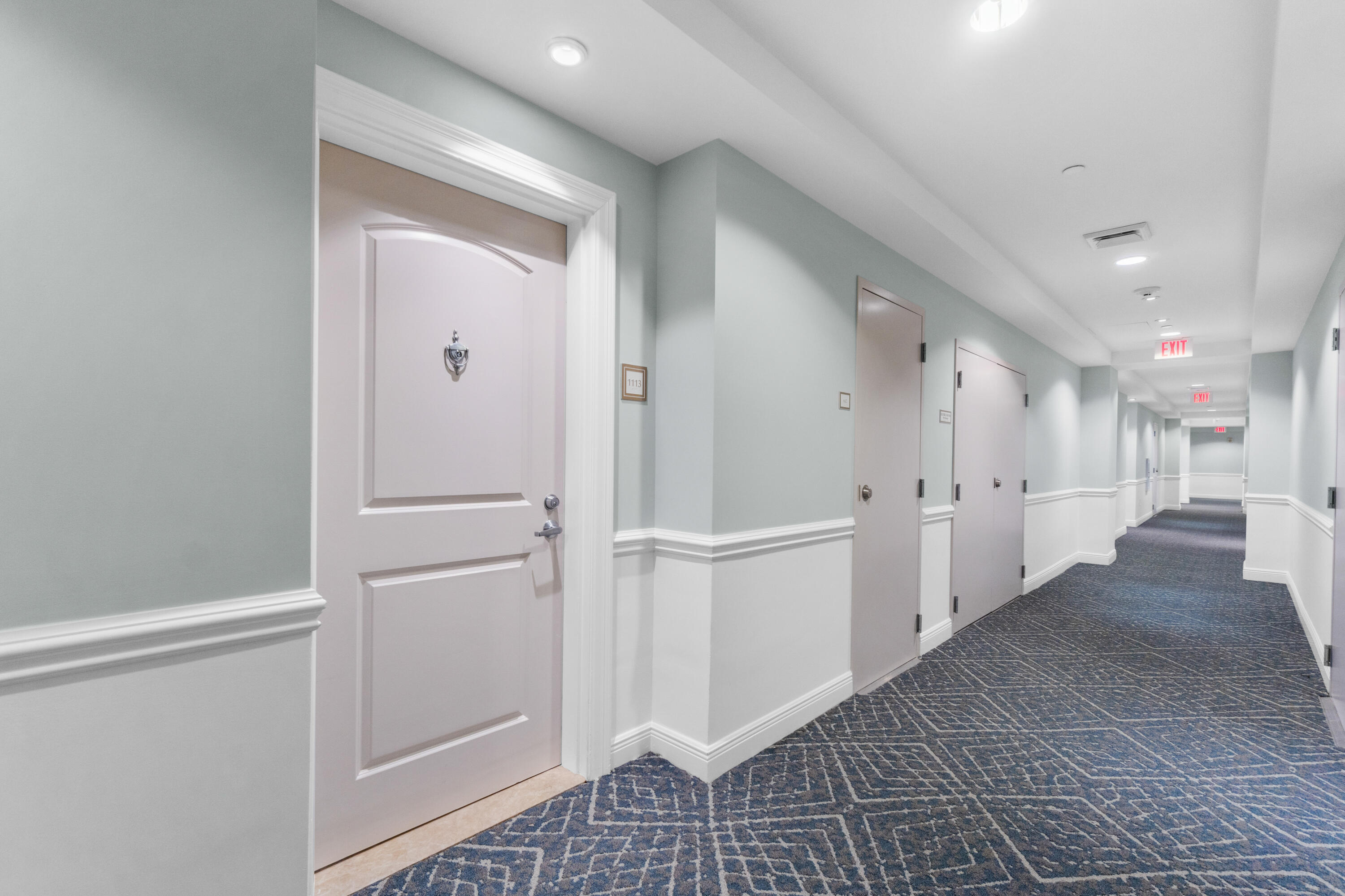 a view of a hallway with white cabinets