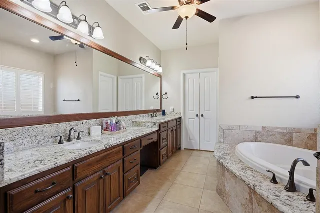 a spacious bathroom with a granite countertop sink a mirror a bathtub and shower