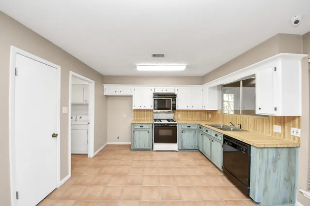 a large kitchen with stainless steel appliances granite countertop a stove refrigerator and a sink