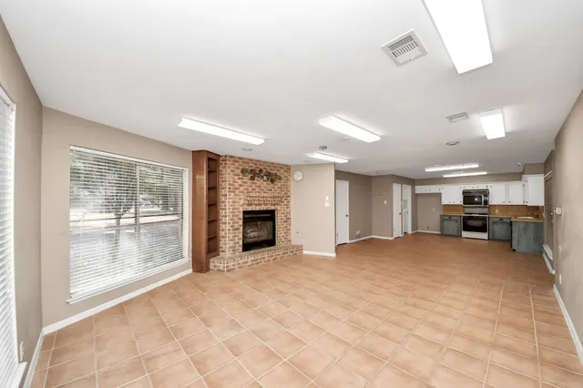 a view of an empty room with a fireplace and a window