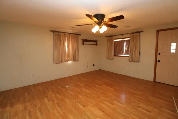a view of an empty room with a chandelier fan and a window