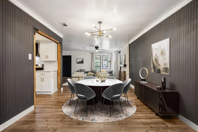 a dining room with wooden floor a chandelier a wooden table and chairs