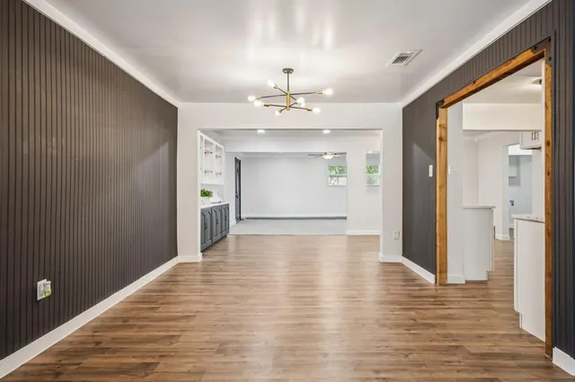 a view of a hallway with wooden floor and chandelier