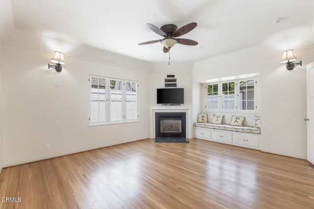 a view of a livingroom with a flat screen tv wooden floor and a ceiling fan
