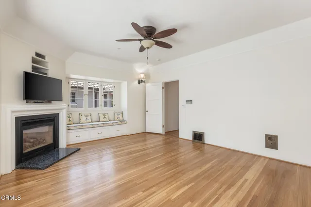 a view of a livingroom with a fireplace a ceiling fan and wooden floor