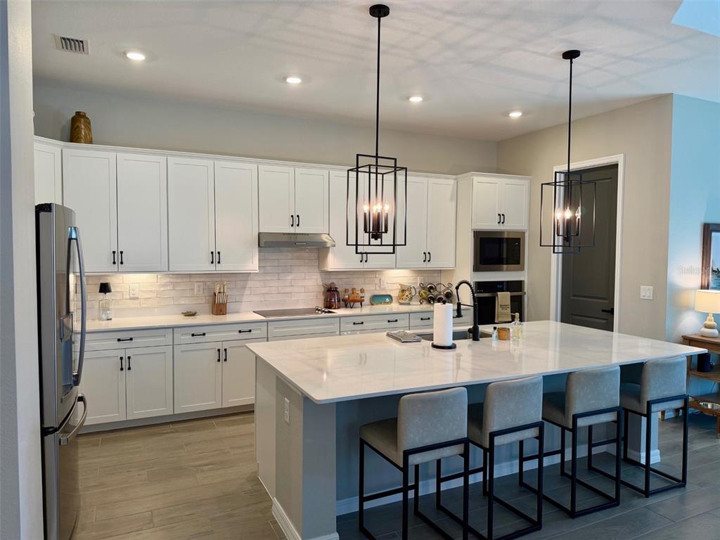 17577 Santorini Court Venice, FL 34293 - Photo 3 of 54 a kitchen with stainless steel appliances granite countertop a sink a stove a refrigerator and island with wooden floor
