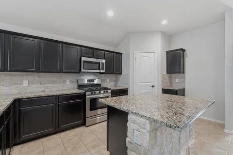 a kitchen with granite countertop a sink and a stove top oven with wooden floor