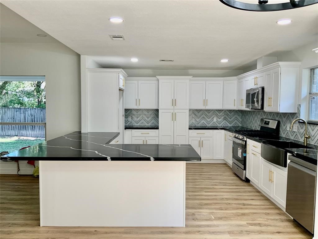 206 Doncaster Conroe, TX 77303 - Photo 5 of 28 a kitchen with kitchen island granite countertop a stove a sink and white cabinets