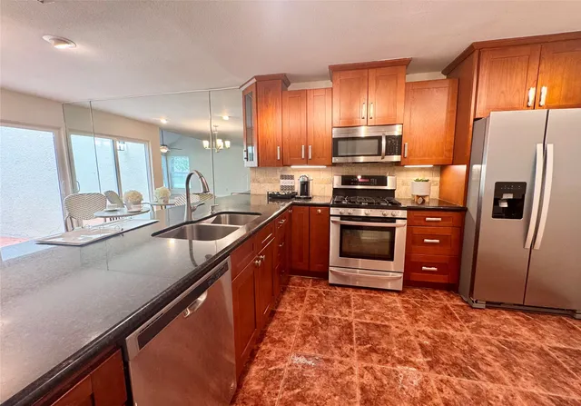 a kitchen with stainless steel appliances granite countertop a refrigerator a stove a sink and a oven