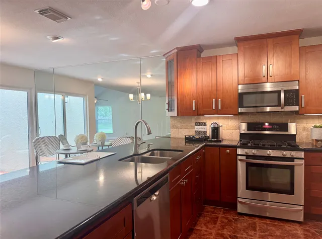 a kitchen with stainless steel appliances a sink a stove cabinets and a dining table