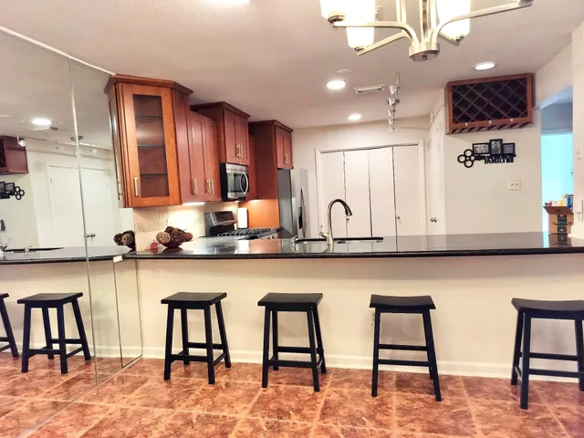a kitchen with stainless steel appliances granite countertop table chairs sink and cabinets