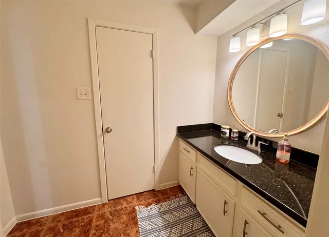 a bathroom with a granite countertop sink and a mirror
