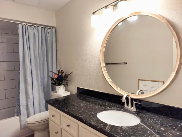a bathroom with a granite countertop sink and a mirror
