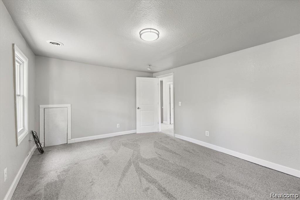 3140 Moore Street Inkster, MI 48141 - Photo 9 of 18 Spacious room featuring plush gray carpeting, neutral wall finishes, and a contemporary ceiling light fixture