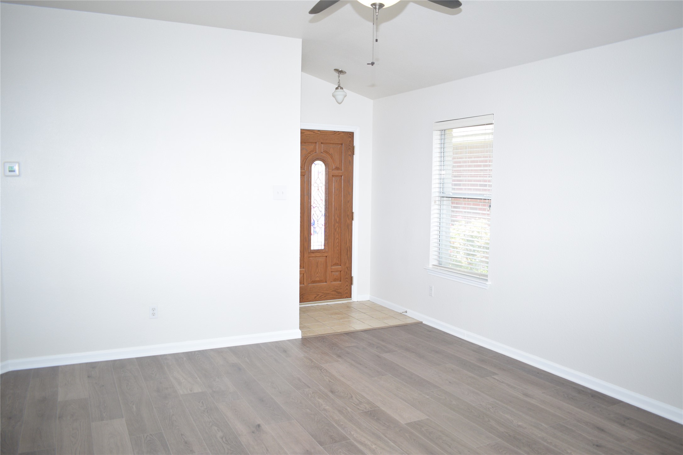 3209 Port Anne Way Leander, TX 78641 - Photo 11 of 30 Living area featuring grey wood-finish flooring, crisp white walls, and a large window with horizontal blinds