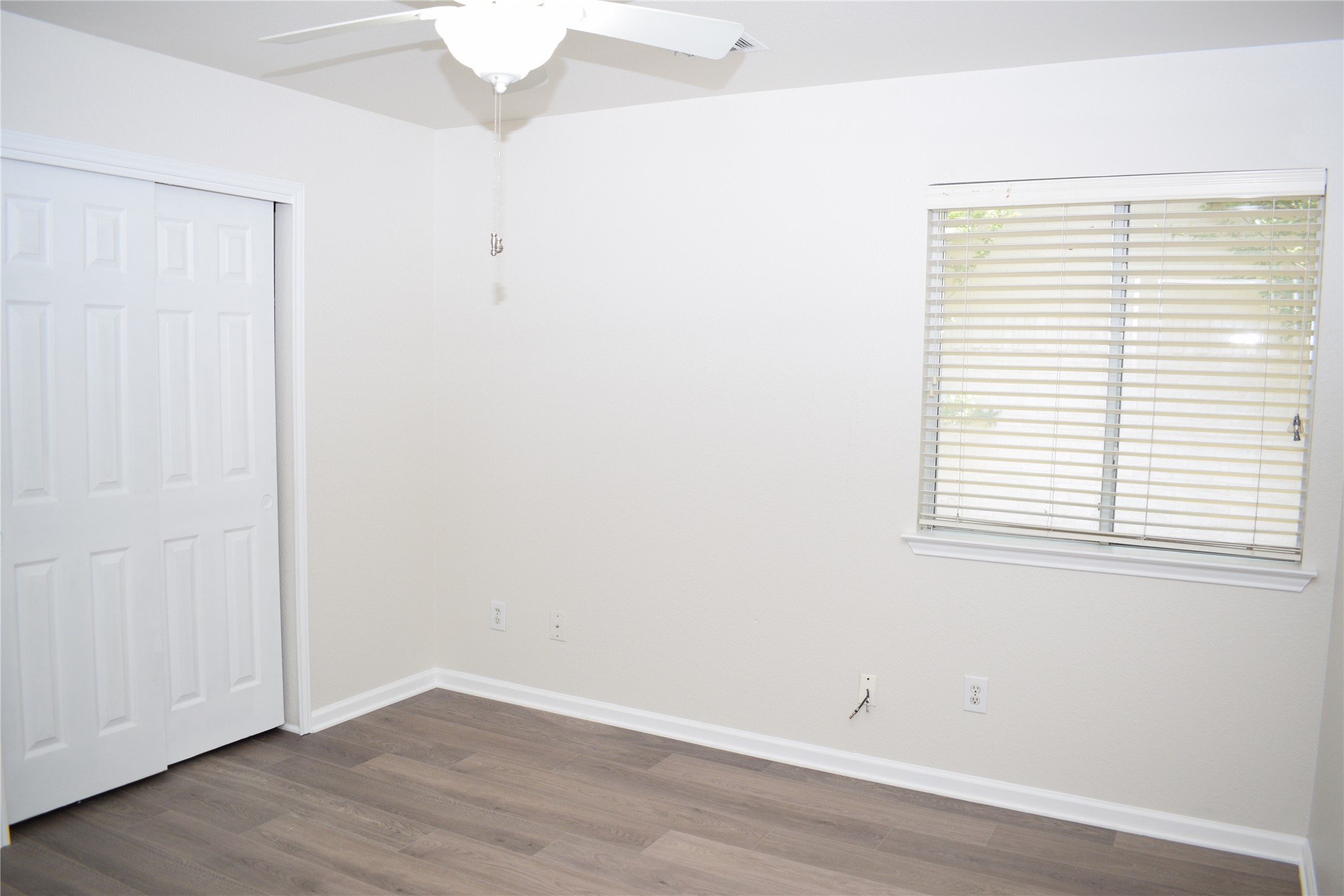 3209 Port Anne Way Leander, TX 78641 - Photo 16 of 30 Room featuring neutral wall tones, wood-finish flooring, a ceiling fan with integrated lighting, a window with horizontal blinds, and a bi-fold closet door
