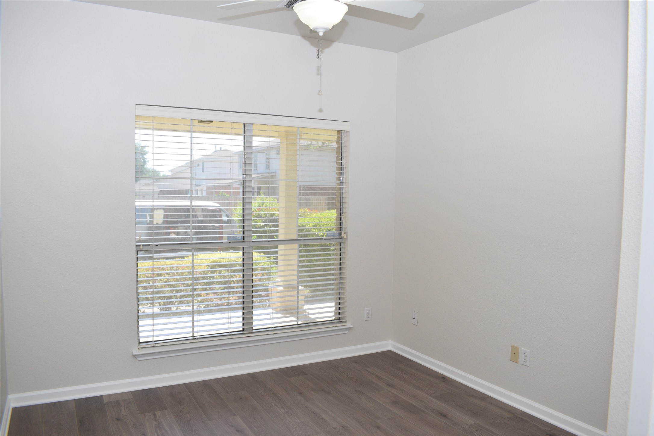 3209 Port Anne Way Leander, TX 78641 - Photo 17 of 30 Light-filled room featuring a large window, wood-finish flooring, white baseboards, and a ceiling fan with integrated lighting