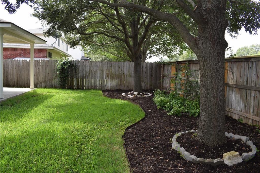 3209 Port Anne Way Leander, TX 78641 - Photo 22 of 30 Expansive backyard with a manicured lawn, established trees, and a mulched garden bed